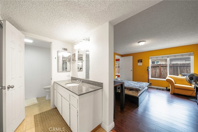 bathroom with a textured ceiling, toilet, vanity, and hardwood / wood-style floors