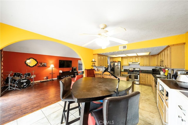 kitchen with stainless steel appliances, light hardwood / wood-style floors, ceiling fan, and a textured ceiling