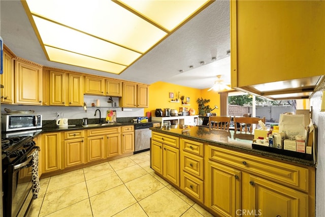 kitchen featuring ceiling fan, light tile patterned flooring, sink, a textured ceiling, and appliances with stainless steel finishes