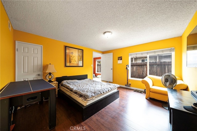 bedroom with multiple windows, a textured ceiling, and dark wood-type flooring