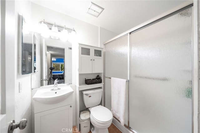 bathroom with a shower with door, vanity, and toilet