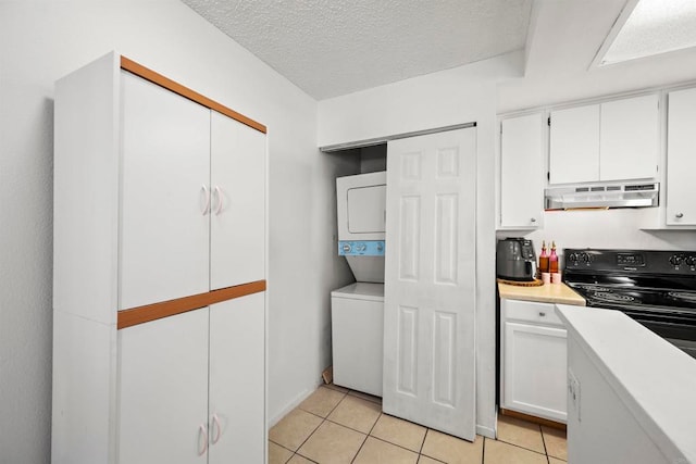 kitchen featuring black range with electric stovetop, white cabinets, light tile patterned floors, and stacked washing maching and dryer