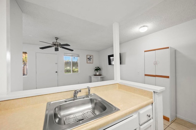 kitchen featuring a textured ceiling, sink, white cabinetry, light tile patterned floors, and ceiling fan