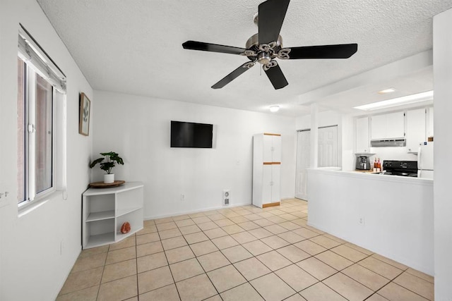 empty room with ceiling fan, light tile patterned floors, and a textured ceiling