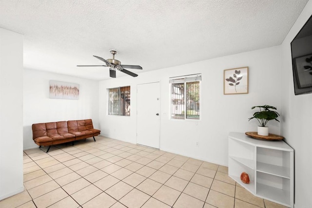 living area featuring a textured ceiling, light tile patterned floors, and ceiling fan