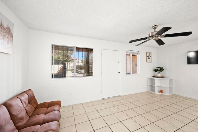 living room with ceiling fan, a textured ceiling, and light tile patterned floors