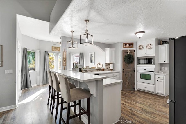 kitchen featuring a kitchen bar, white cabinetry, dark wood-type flooring, and stainless steel appliances