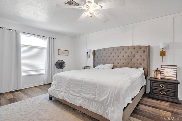 bedroom featuring ceiling fan, wood-type flooring, and a textured ceiling