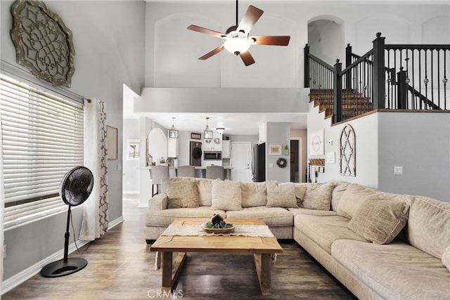 living room with a towering ceiling, hardwood / wood-style flooring, and ceiling fan