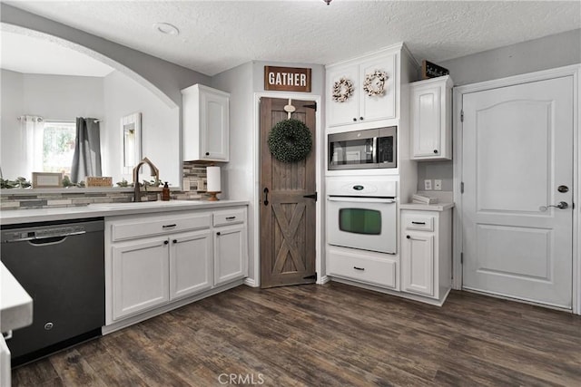 kitchen featuring white oven, dark wood-type flooring, dishwasher, white cabinetry, and stainless steel microwave