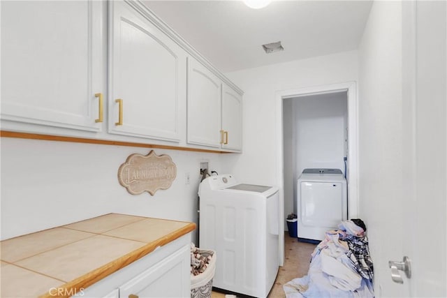 laundry room featuring washing machine and clothes dryer and cabinets