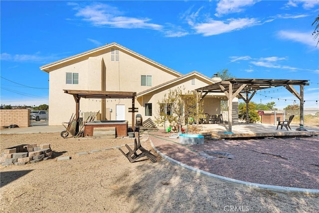 rear view of property featuring a pergola and a hot tub