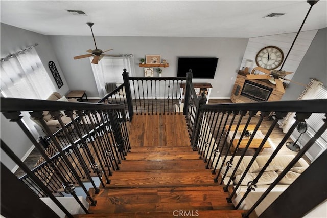 staircase with hardwood / wood-style floors and ceiling fan