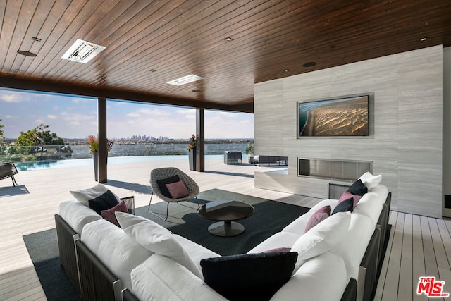 living room featuring wood ceiling, light hardwood / wood-style floors, a fireplace, a water view, and expansive windows