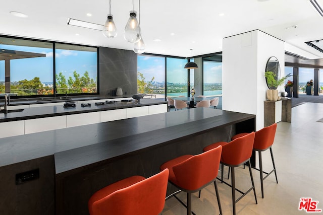 kitchen featuring a kitchen breakfast bar, hanging light fixtures, a wealth of natural light, and white cabinets