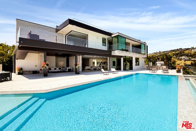 rear view of property featuring a balcony, an outdoor living space, and a patio area