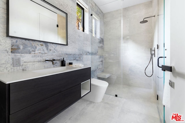 bathroom with tile walls, a shower with door, vanity, and toilet