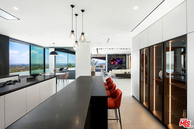 kitchen featuring expansive windows, pendant lighting, a kitchen bar, and white cabinetry