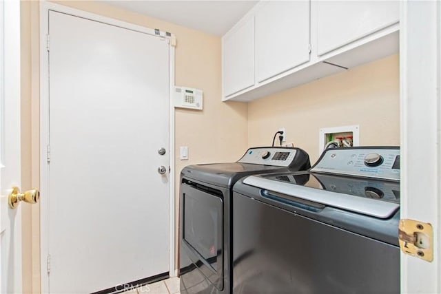 laundry area featuring washing machine and dryer, light tile patterned flooring, and cabinets