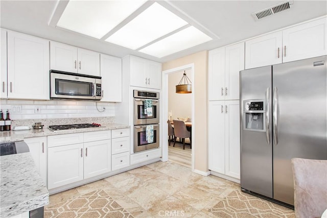 kitchen featuring light stone countertops, appliances with stainless steel finishes, backsplash, and white cabinetry