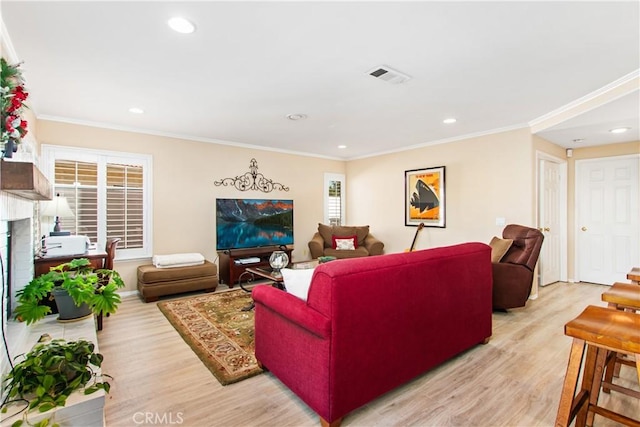 living room featuring light hardwood / wood-style floors, crown molding, and a brick fireplace