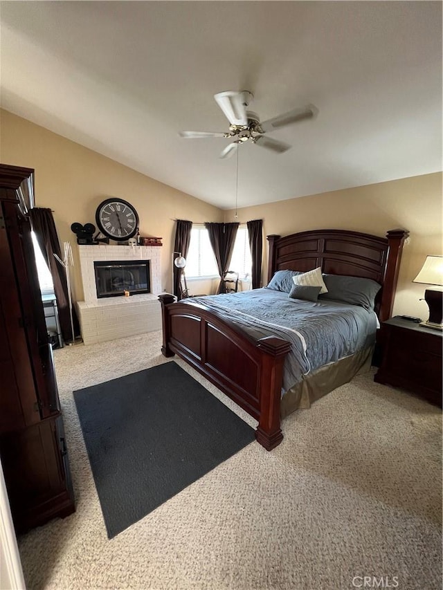 bedroom featuring ceiling fan, light colored carpet, lofted ceiling, and a brick fireplace