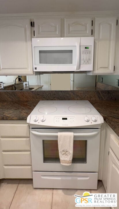 kitchen with light tile patterned floors, white cabinets, and white appliances