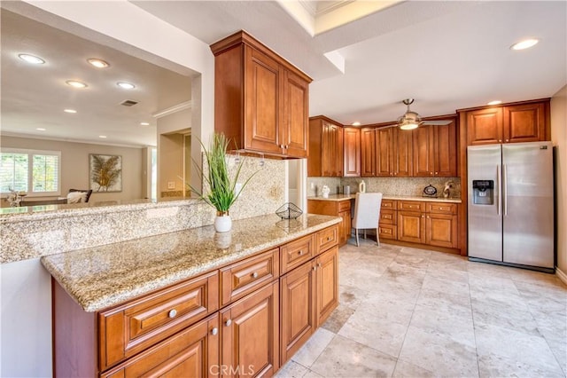 kitchen with tasteful backsplash, light stone counters, ceiling fan, and stainless steel refrigerator with ice dispenser