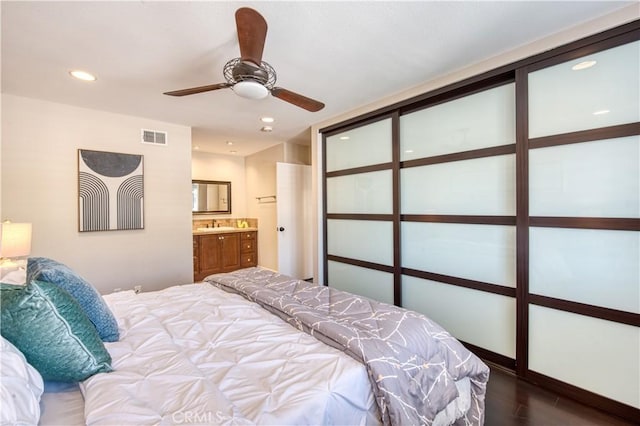 bedroom with ensuite bathroom, ceiling fan, and dark hardwood / wood-style floors