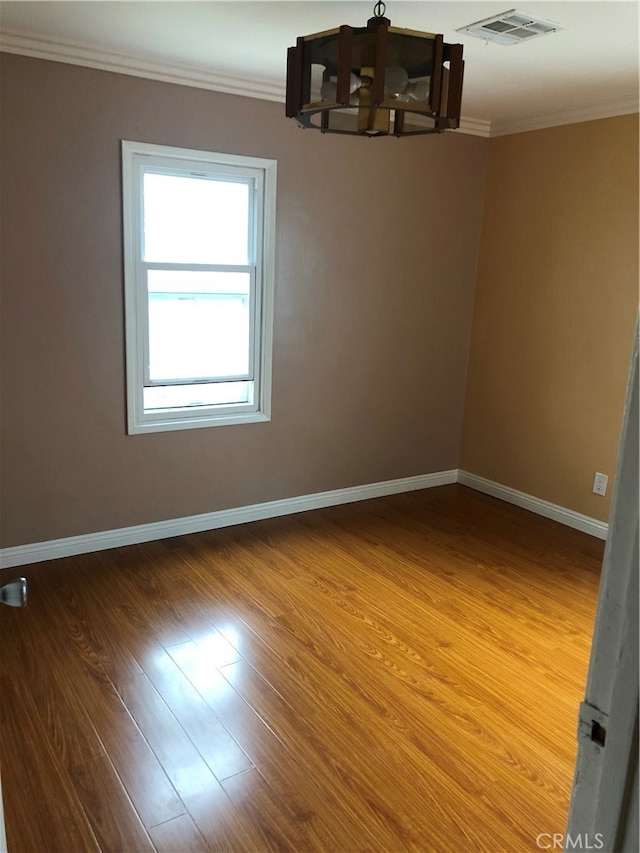 empty room with hardwood / wood-style floors and crown molding