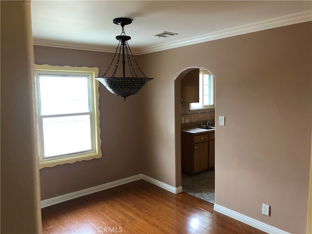 unfurnished dining area featuring crown molding, dark hardwood / wood-style floors, and a wealth of natural light