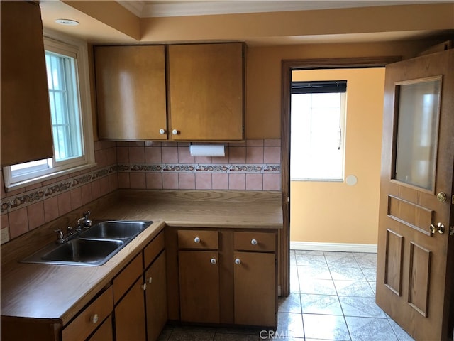 kitchen featuring light tile patterned floors, backsplash, sink, and crown molding