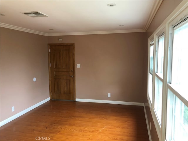 empty room featuring wood-type flooring and ornamental molding