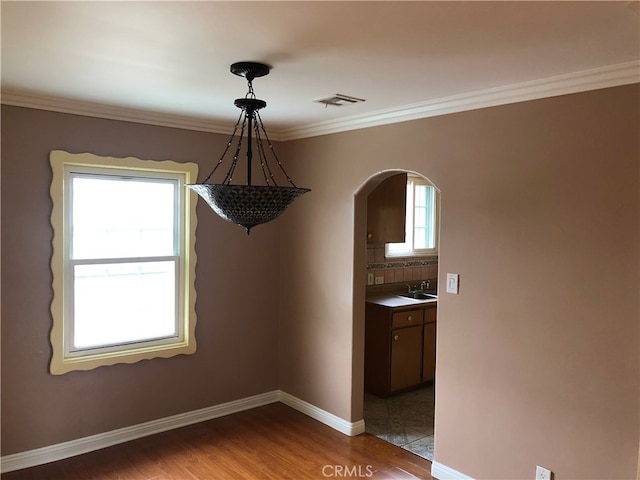 unfurnished dining area with sink, plenty of natural light, light hardwood / wood-style floors, and crown molding