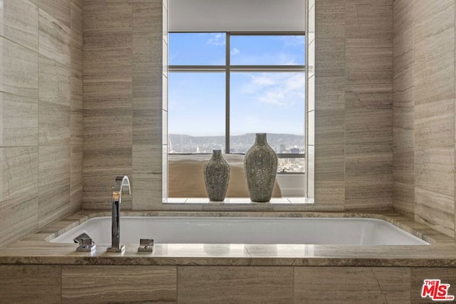 bathroom with a relaxing tiled tub, a mountain view, and a wealth of natural light