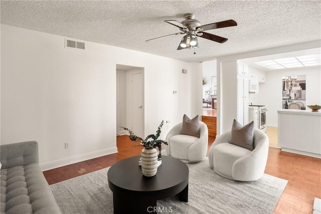 living room featuring ceiling fan and a textured ceiling