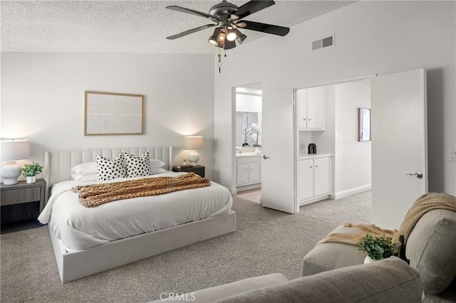 bedroom featuring light carpet, ensuite bathroom, a textured ceiling, vaulted ceiling, and ceiling fan