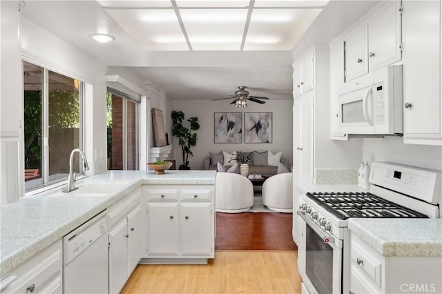 kitchen featuring light wood-type flooring, white appliances, ceiling fan, sink, and white cabinetry