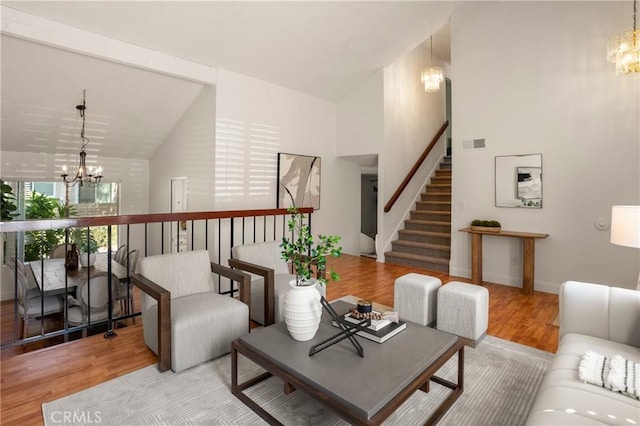 living room with a chandelier, high vaulted ceiling, and light hardwood / wood-style flooring