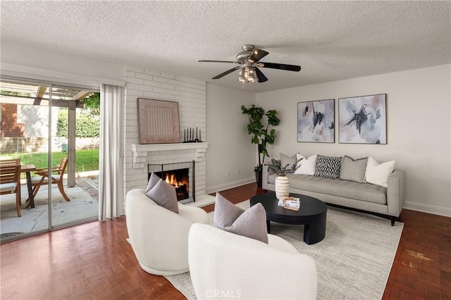 living room featuring ceiling fan, parquet floors, a textured ceiling, and a brick fireplace