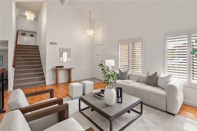 living room with a notable chandelier, light hardwood / wood-style floors, and high vaulted ceiling