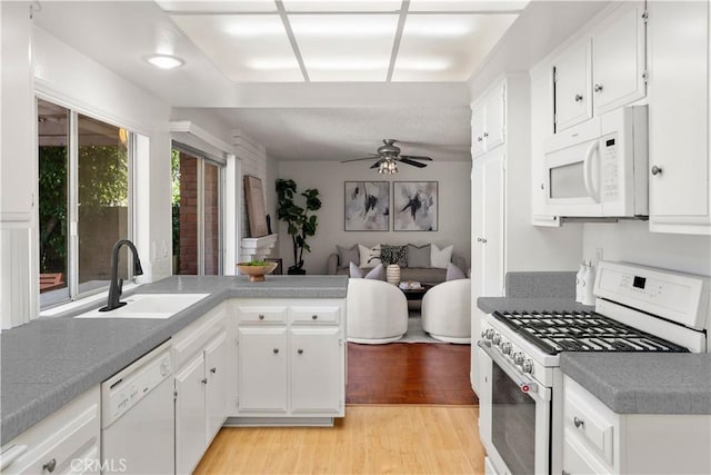 kitchen with white appliances, light hardwood / wood-style flooring, white cabinetry, and sink