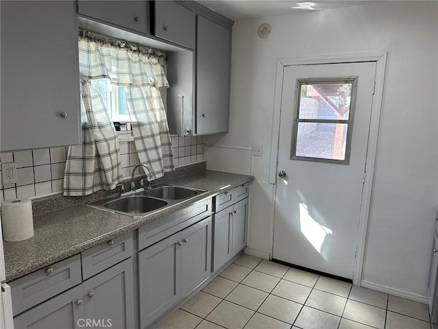 kitchen with light tile patterned flooring, tasteful backsplash, gray cabinetry, and sink