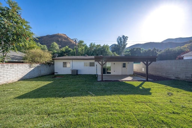 rear view of property featuring a mountain view, cooling unit, and a lawn