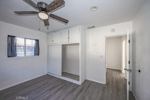 unfurnished bedroom with wood-type flooring, a closet, and ceiling fan