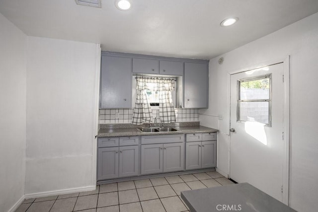 kitchen featuring backsplash, gray cabinetry, light tile patterned floors, and sink