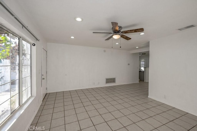 spare room featuring ceiling fan, light tile patterned floors, and a healthy amount of sunlight