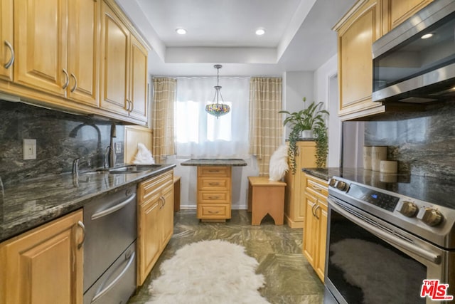 kitchen with dark stone countertops, hanging light fixtures, appliances with stainless steel finishes, and tasteful backsplash