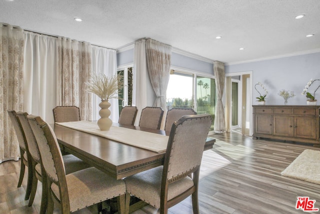 dining area featuring ornamental molding, a textured ceiling, and light wood-type flooring