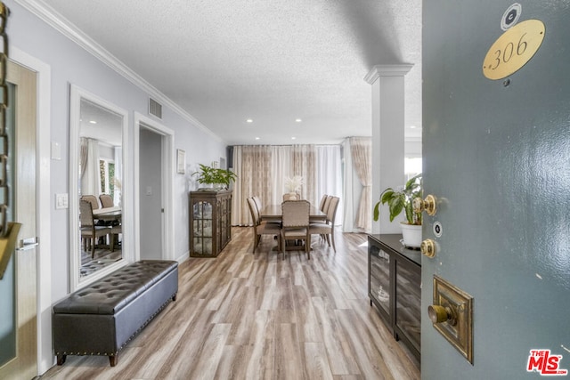 dining room with a textured ceiling, light hardwood / wood-style floors, and ornamental molding